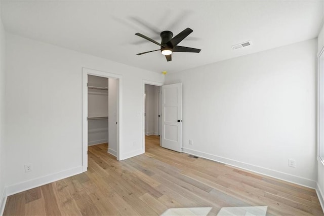 unfurnished bedroom with visible vents, baseboards, a walk in closet, and light wood finished floors