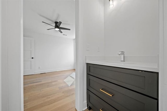 bathroom with vanity, a ceiling fan, wood finished floors, baseboards, and visible vents