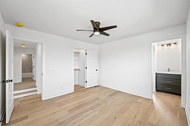 unfurnished bedroom with a walk in closet, baseboards, and light wood finished floors