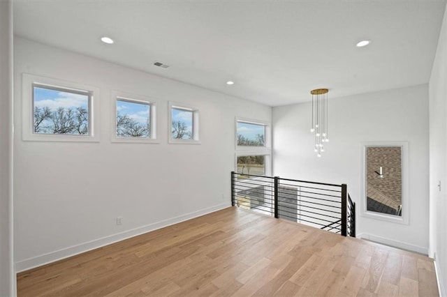 empty room with light wood finished floors, visible vents, recessed lighting, and baseboards