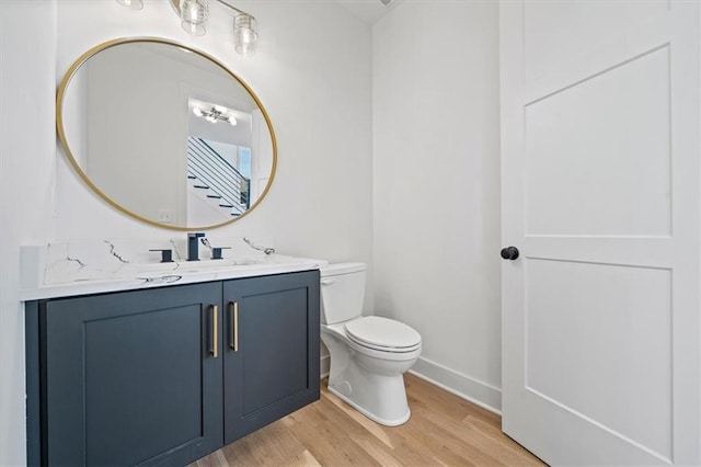 bathroom featuring toilet, vanity, baseboards, and wood finished floors