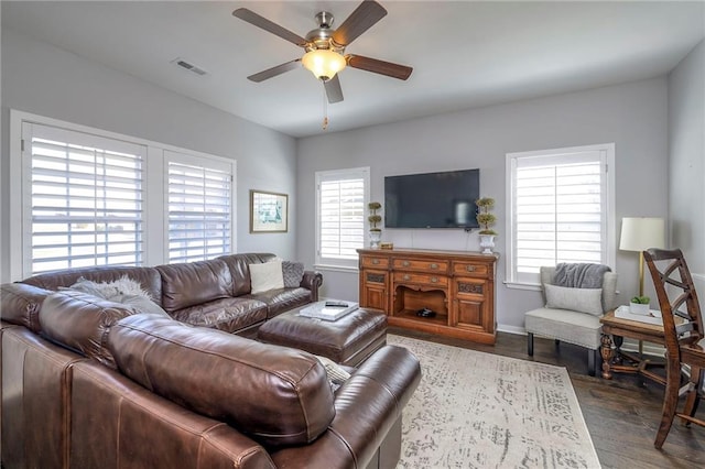 living area with plenty of natural light, visible vents, dark wood-style flooring, and ceiling fan