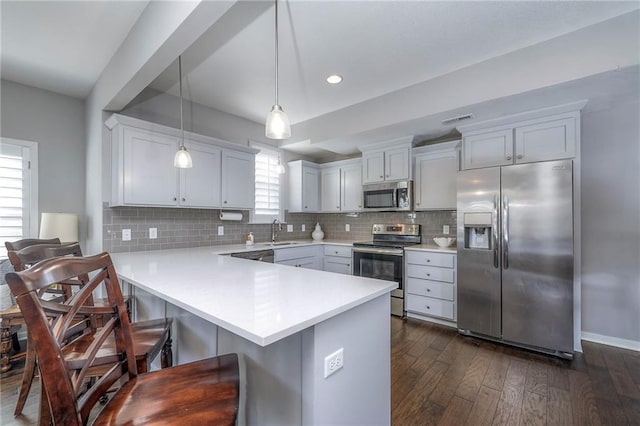 kitchen featuring visible vents, a sink, appliances with stainless steel finishes, a peninsula, and light countertops