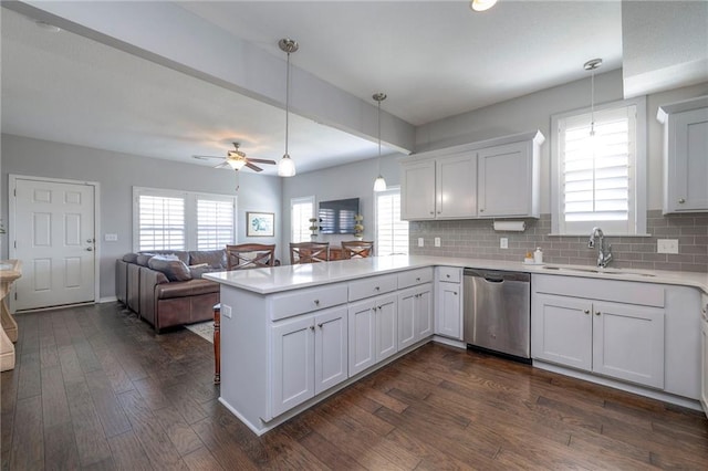 kitchen with a sink, dark wood finished floors, a peninsula, light countertops, and dishwasher