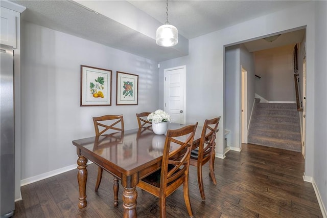 dining space featuring dark wood finished floors, stairs, and baseboards