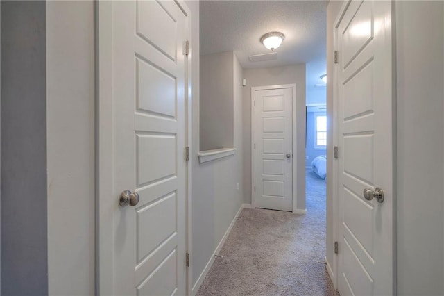 corridor with baseboards, carpet, and a textured ceiling