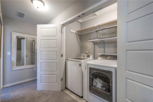 washroom featuring visible vents, laundry area, a textured ceiling, light colored carpet, and washer and clothes dryer