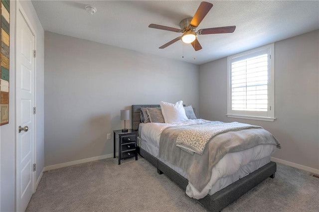 bedroom featuring a ceiling fan, baseboards, carpet floors, and a textured ceiling