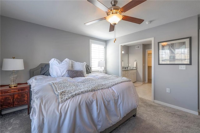 bedroom with visible vents, baseboards, light carpet, ensuite bath, and a ceiling fan