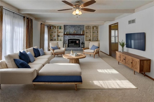 living area featuring visible vents, light carpet, beamed ceiling, a ceiling fan, and a stone fireplace