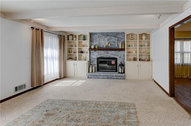 unfurnished living room with visible vents, carpet floors, baseboards, beam ceiling, and a fireplace