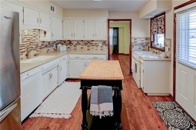 kitchen featuring white appliances, visible vents, a sink, light countertops, and light wood-style floors