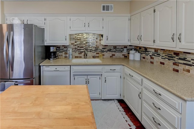 kitchen with visible vents, a sink, backsplash, freestanding refrigerator, and dishwasher