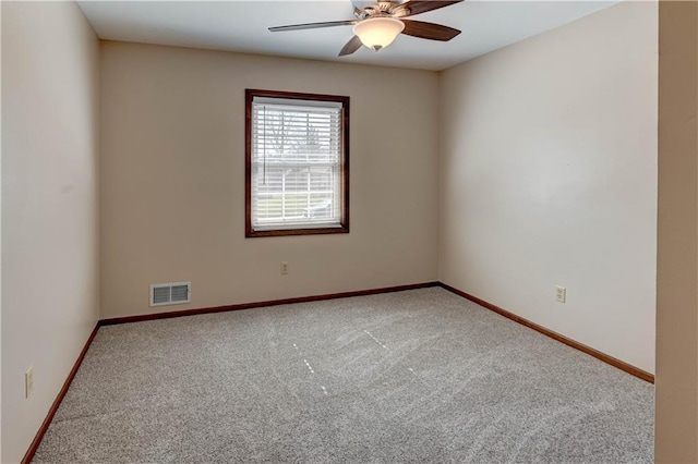 carpeted spare room with visible vents, baseboards, and ceiling fan