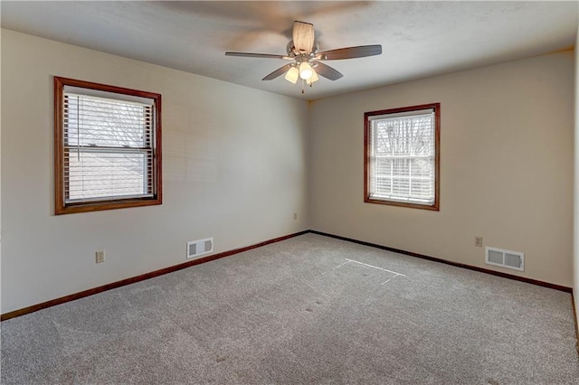 carpeted empty room with visible vents, baseboards, and a ceiling fan