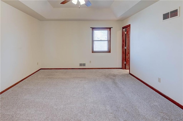 spare room featuring a raised ceiling, baseboards, visible vents, and ceiling fan