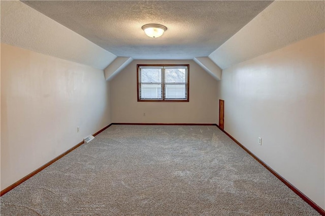 bonus room featuring lofted ceiling, carpet flooring, baseboards, and visible vents