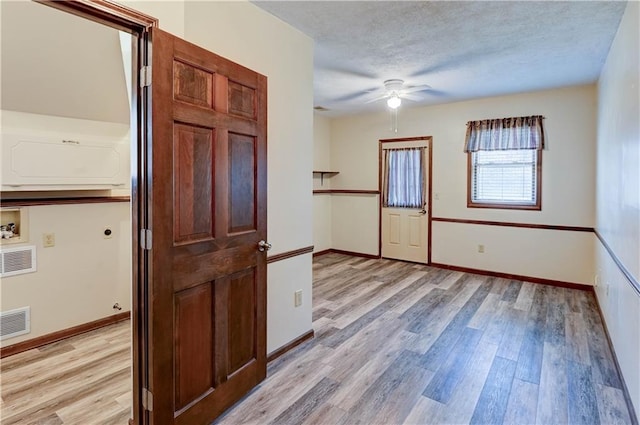 unfurnished room featuring visible vents, baseboards, light wood-style floors, and a textured ceiling