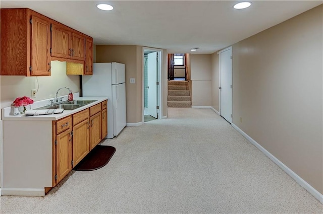 kitchen with light countertops, freestanding refrigerator, baseboards, and a sink