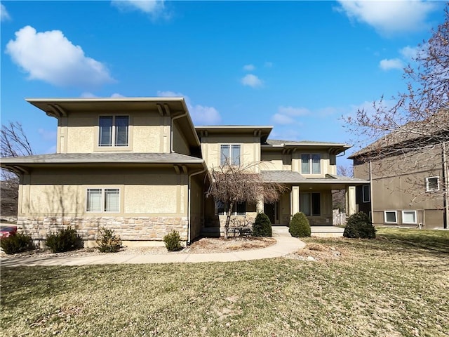 prairie-style house featuring stone siding, stucco siding, and a front lawn