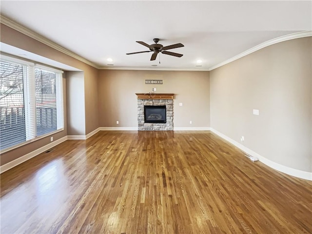 unfurnished living room with baseboards, a stone fireplace, wood finished floors, and ornamental molding