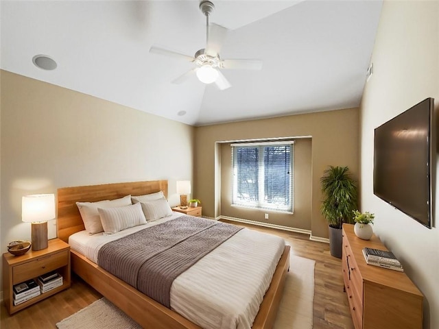 bedroom with a ceiling fan, vaulted ceiling, and wood finished floors