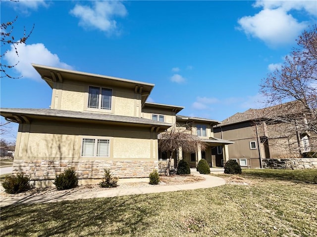 rear view of property with stone siding, stucco siding, and a yard