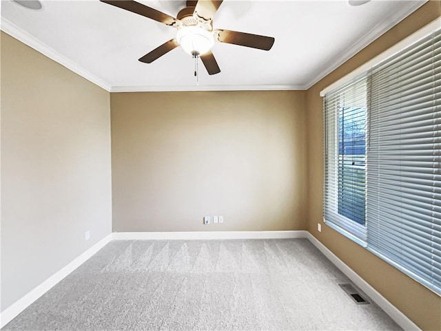 carpeted empty room featuring crown molding, baseboards, visible vents, and ceiling fan