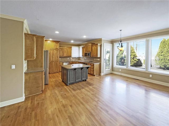 kitchen with baseboards, a kitchen island, ornamental molding, stainless steel appliances, and light wood-style floors