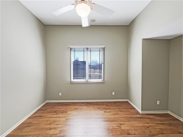 empty room featuring baseboards, wood finished floors, and a ceiling fan