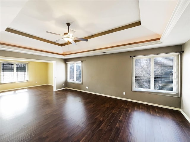 empty room with wood finished floors, baseboards, a tray ceiling, ornamental molding, and ceiling fan