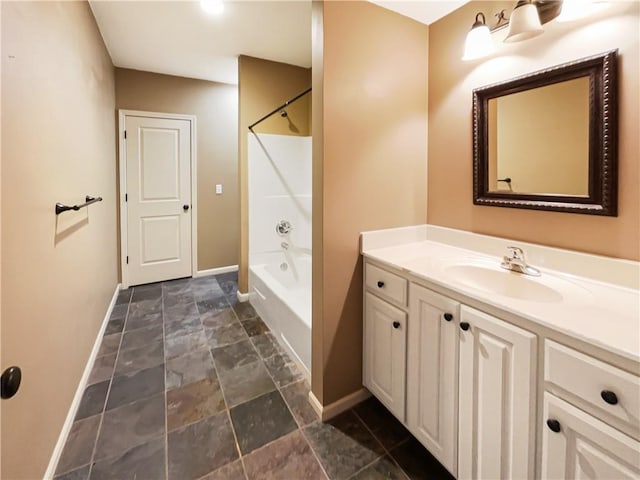 full bath featuring shower / bathing tub combination, baseboards, vanity, and stone finish flooring