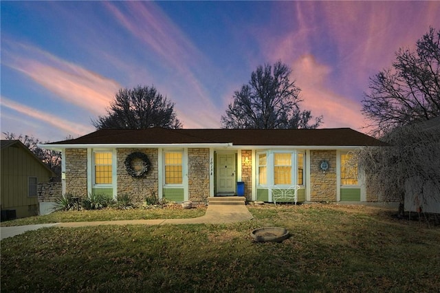 ranch-style home with stone siding and a lawn