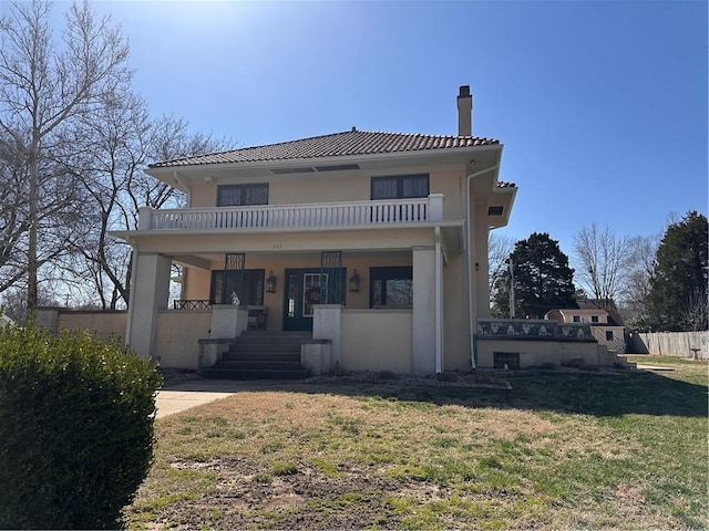 view of front of property with a balcony, a porch, stucco siding, a chimney, and a tiled roof