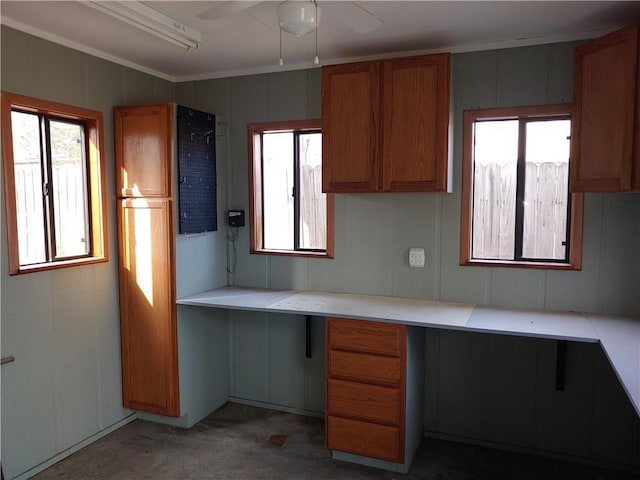 kitchen featuring a healthy amount of sunlight, built in study area, ceiling fan, light countertops, and brown cabinets