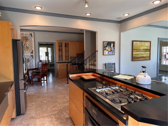 kitchen featuring arched walkways, dark countertops, appliances with stainless steel finishes, and crown molding