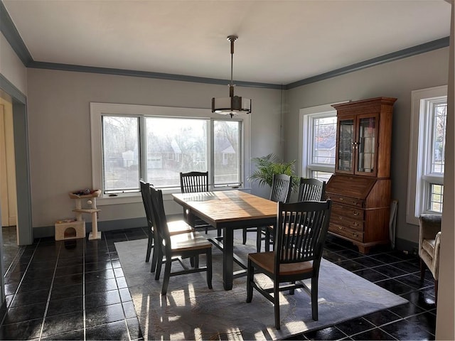 dining area featuring dark tile patterned floors, baseboards, and ornamental molding