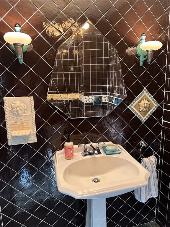 bathroom with a sink, backsplash, and tile walls