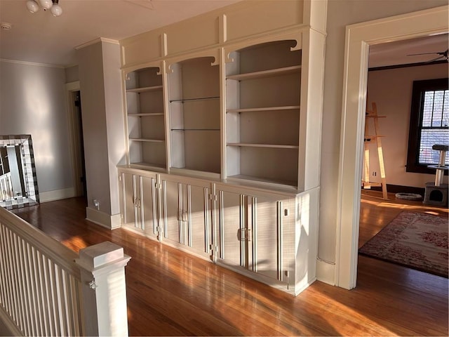 hallway featuring wood finished floors, baseboards, and ornamental molding