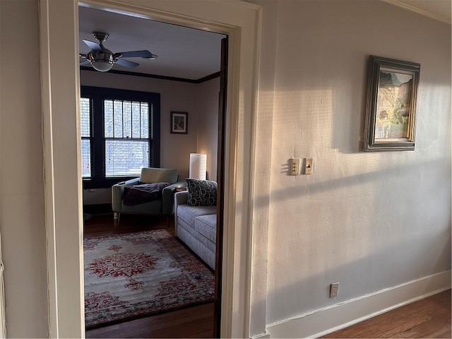 corridor with ornamental molding, baseboards, and wood finished floors