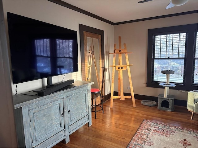 home office with a ceiling fan, crown molding, baseboards, and wood finished floors