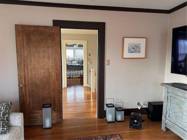 hall with ornamental molding and wood finished floors