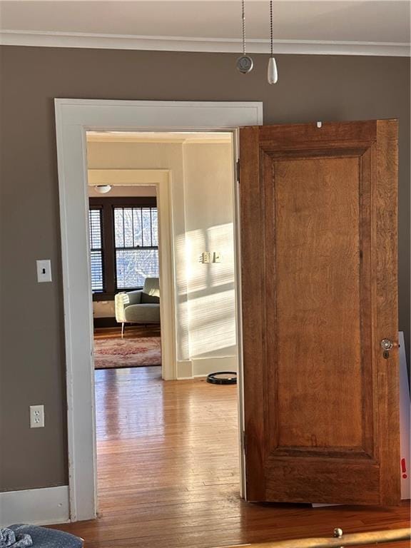 hallway with crown molding, baseboards, and wood finished floors