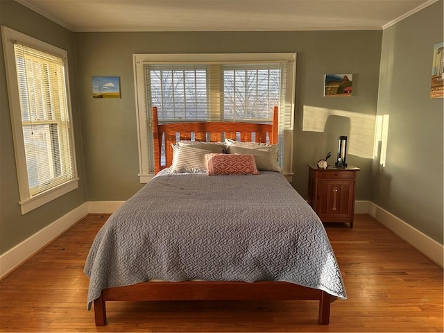 bedroom with baseboards, light wood-style floors, and ornamental molding