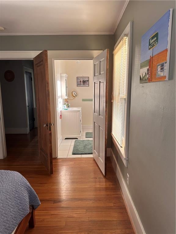 hallway with light wood-style floors, baseboards, and ornamental molding