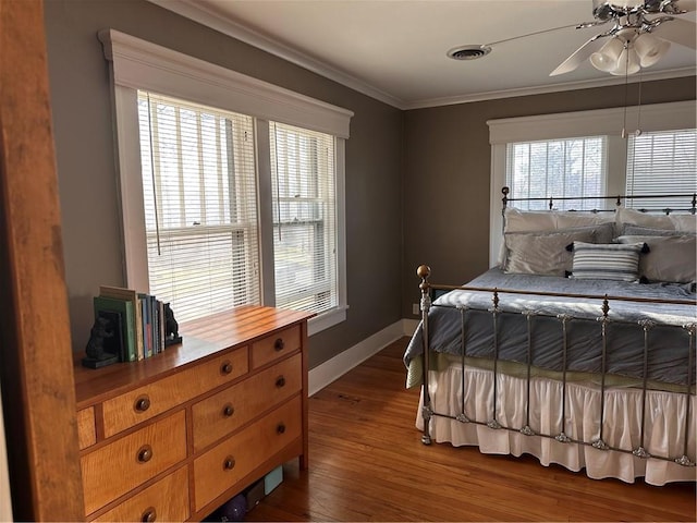 bedroom featuring visible vents, wood finished floors, crown molding, baseboards, and ceiling fan