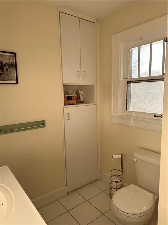 bathroom with tile patterned floors, baseboards, and toilet