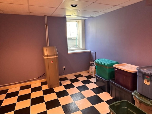 basement with tile patterned floors, a paneled ceiling, and baseboards