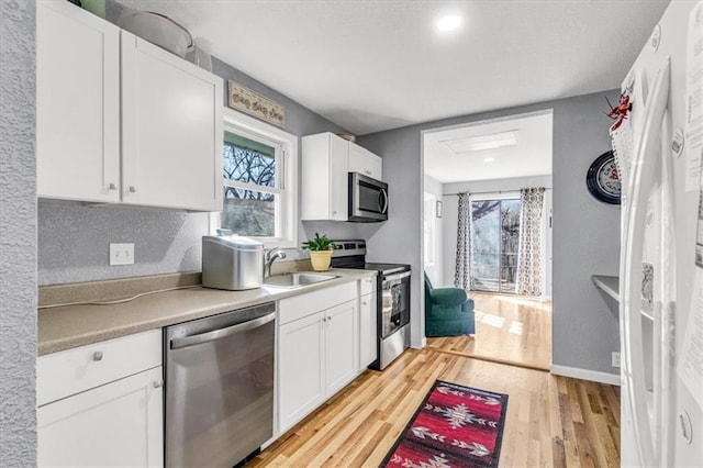 kitchen with white cabinetry, light wood-style flooring, appliances with stainless steel finishes, and a sink