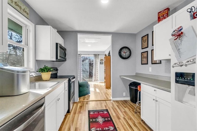 kitchen featuring a sink, light wood-style floors, appliances with stainless steel finishes, and white cabinetry